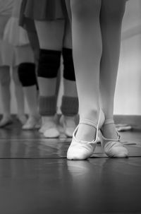 Low section of ballet dancers standing on hardwood floor