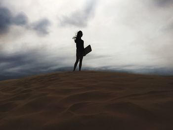 Low angle view of man jumping against cloudy sky