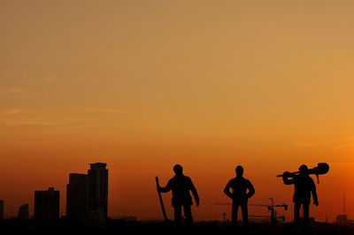 Silhouette people against orange sky