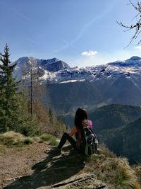 Rear view of backpacker looking at mountains against sky during winter