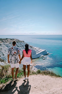 Rear view of friends standing on beach