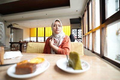 Portrait of young woman sitting on table