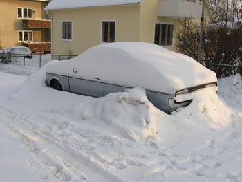 Snow covered car on field by building