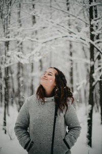 Young woman standing on snow covered tree during winter