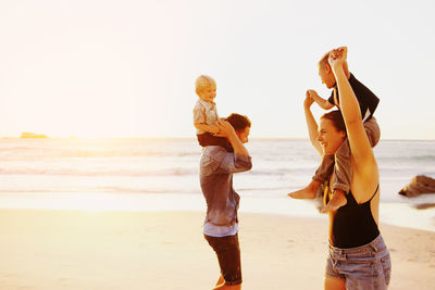 Rear view of women on beach against sky