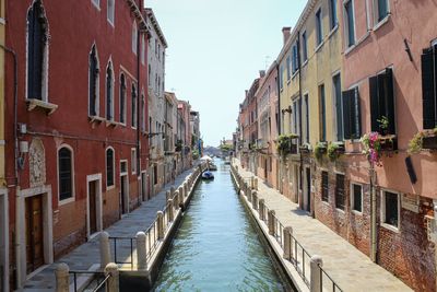 Canal amidst buildings in city against sky