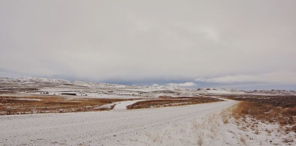 Road leading towards snowcapped mountains against sky