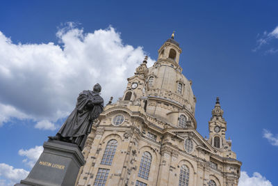 Low angle view of statue amidst buildings against sky