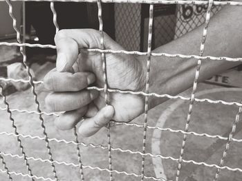 Close-up of human hand in cage