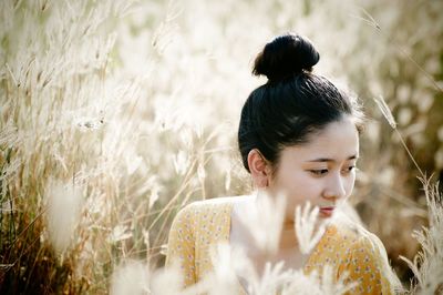 Portrait of young woman looking away on field