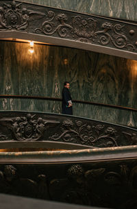 Side view of woman sitting on staircase in building