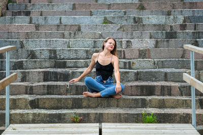 Full length of young woman sitting on staircase