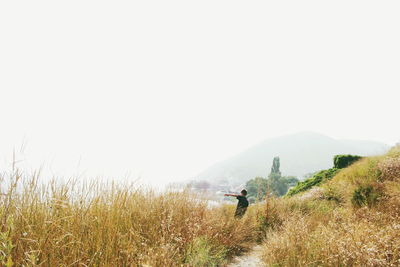 Woman standing on grassy field against clear sky