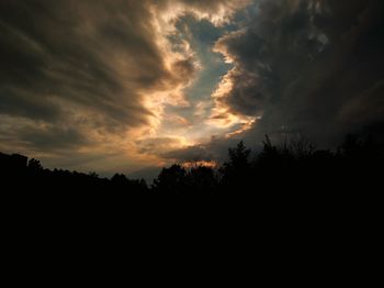 Silhouette of trees against cloudy sky