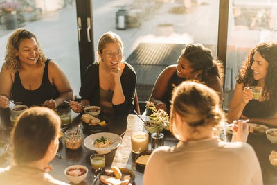 Woman with hand on chin talking to female friends during breakfast at retreat center