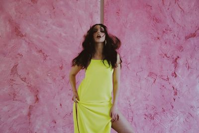 Woman wearing yellow dress on a pastel pink background