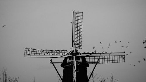 Low angle view of silhouette windmill against clear sky