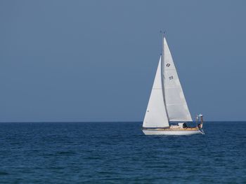 Sailboat sailing on sea against clear sky