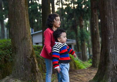 Happy brother and sister standing on land in forest