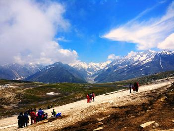 People on snowcapped mountain against sky