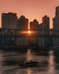 River by buildings against sky during sunset