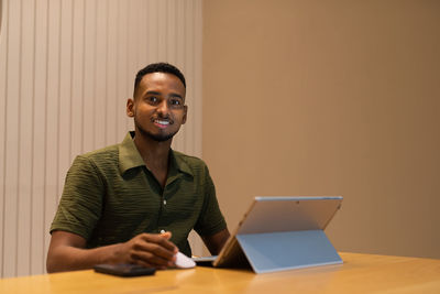 Young man using laptop while sitting on table