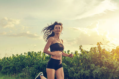 Woman running across the field. dark hair flutters in wind.