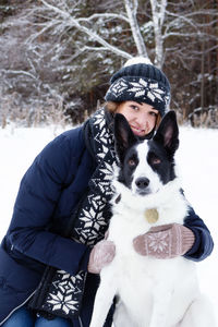 Portrait of woman with dog in snow