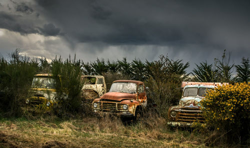 Abandoned car on field against sky