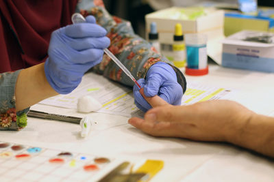 Cropped hands of doctor removing blood sample from patient finger