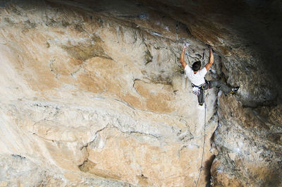 Low angle view of man climbing rocky mountain