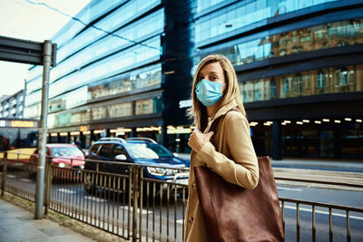 Woman in protective mask walks at city street