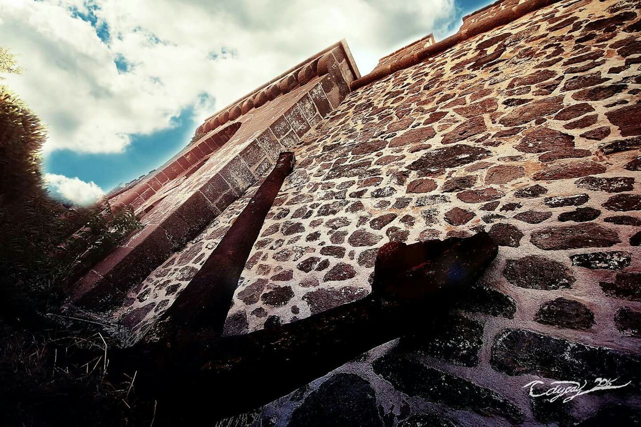 built structure, architecture, building exterior, sky, abandoned, damaged, low angle view, obsolete, cloud - sky, deterioration, old, run-down, house, day, wall - building feature, outdoors, weathered, stone wall, sunlight, brick wall