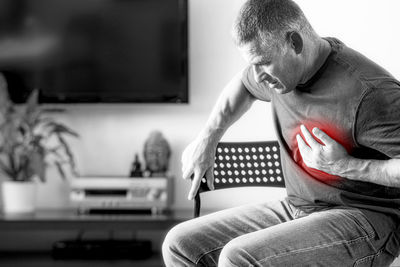 Midsection of man sitting on sofa at home