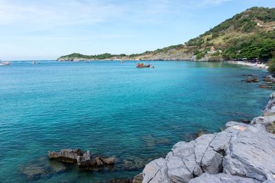 Scenic view of sea by mountain against sky