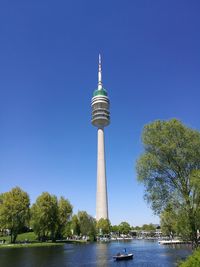 Communications tower in city against clear blue sky