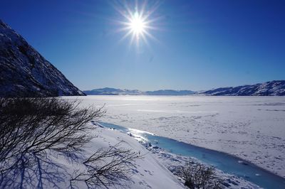 Scenic view of landscape against clear blue sky during winter