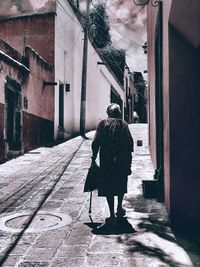 Rear view of woman walking on street amidst buildings