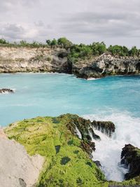 Scenic view of rocks by sea against sky