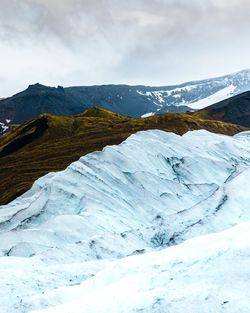 Scenic view of glacier and snowcapped mountains against sky