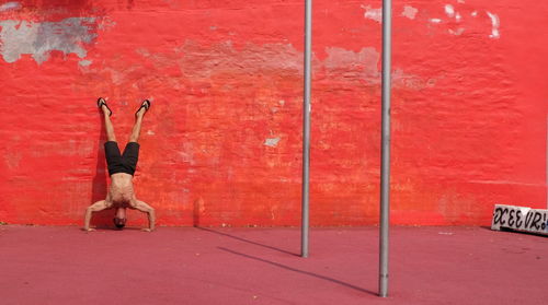 Upside down image of man skateboarding on red wall