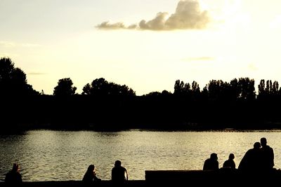 Silhouette people in lake at sunset