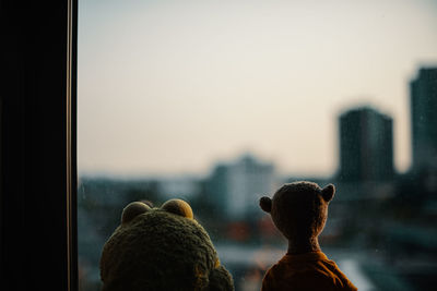 Toys in window against sky during sunset