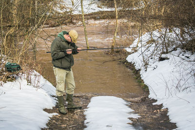 Mid adult man fishing in lake during winter