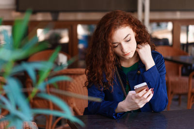 Portrait happy smiling pretty redhead girl sitting in street cafe or co-working