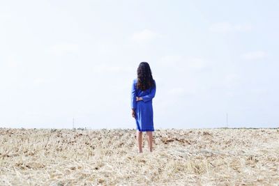 Rear view of woman standing on field against sky