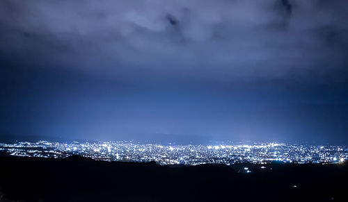 Illuminated cityscape against sky at night