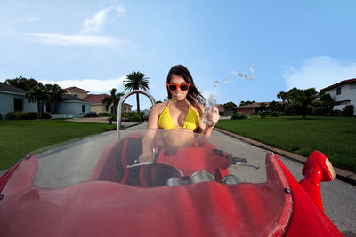 Portrait of angry young woman crushing water bottle while sitting in car