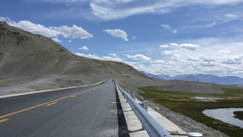 Road by mountains against sky