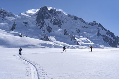 People walking on snow against snow capped mountain and sky